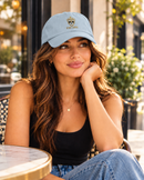 Woman wearing light blue King Eddie signature crest dad hat at an outdoor café